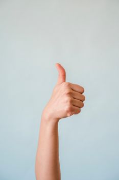 pexels-photo-9017730-9017730 Close-up of a hand showing a thumbs up gesture on a blue background.